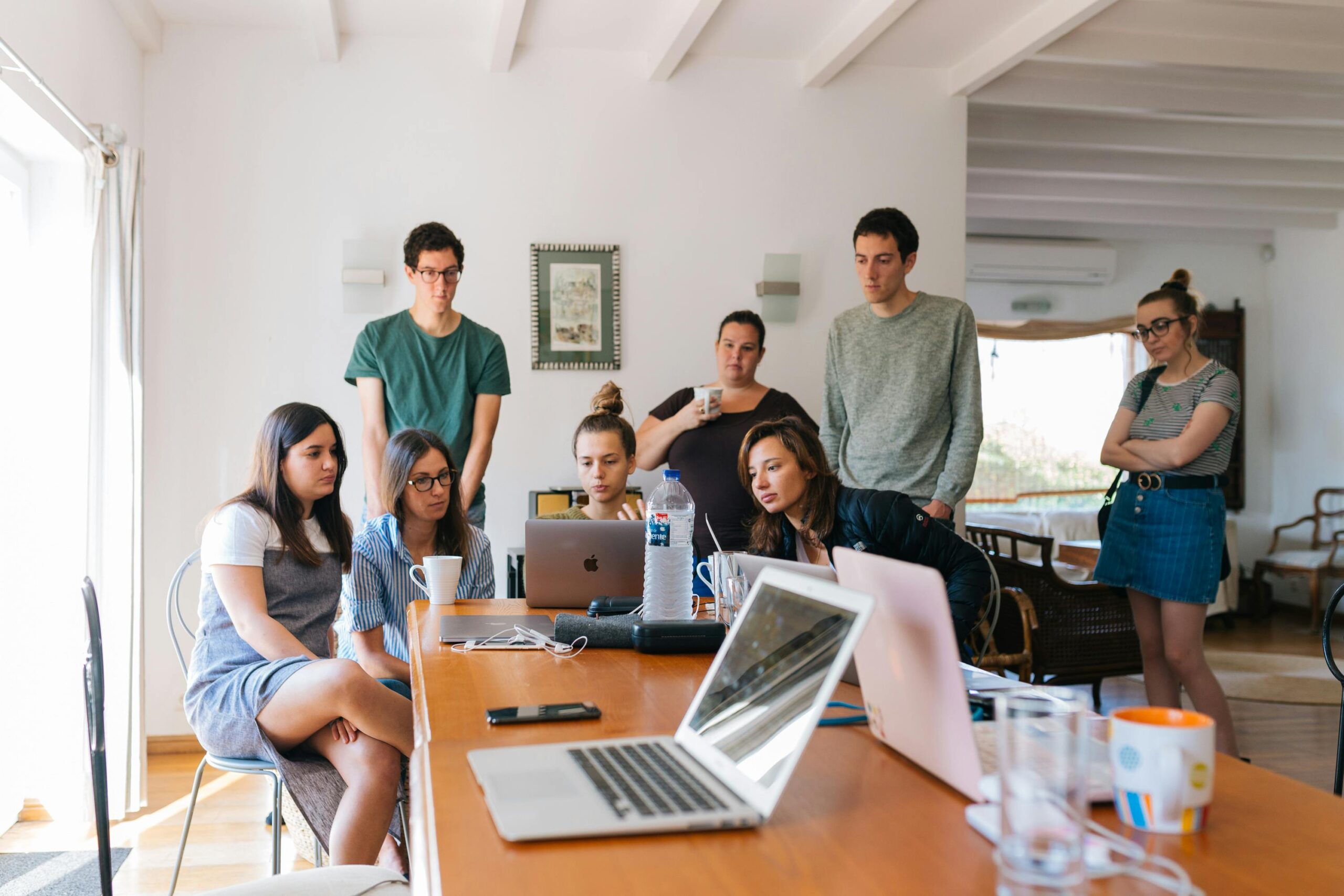 Gruppe junger Menschen arbeitet gemeinsam an einem Tisch mit Laptops